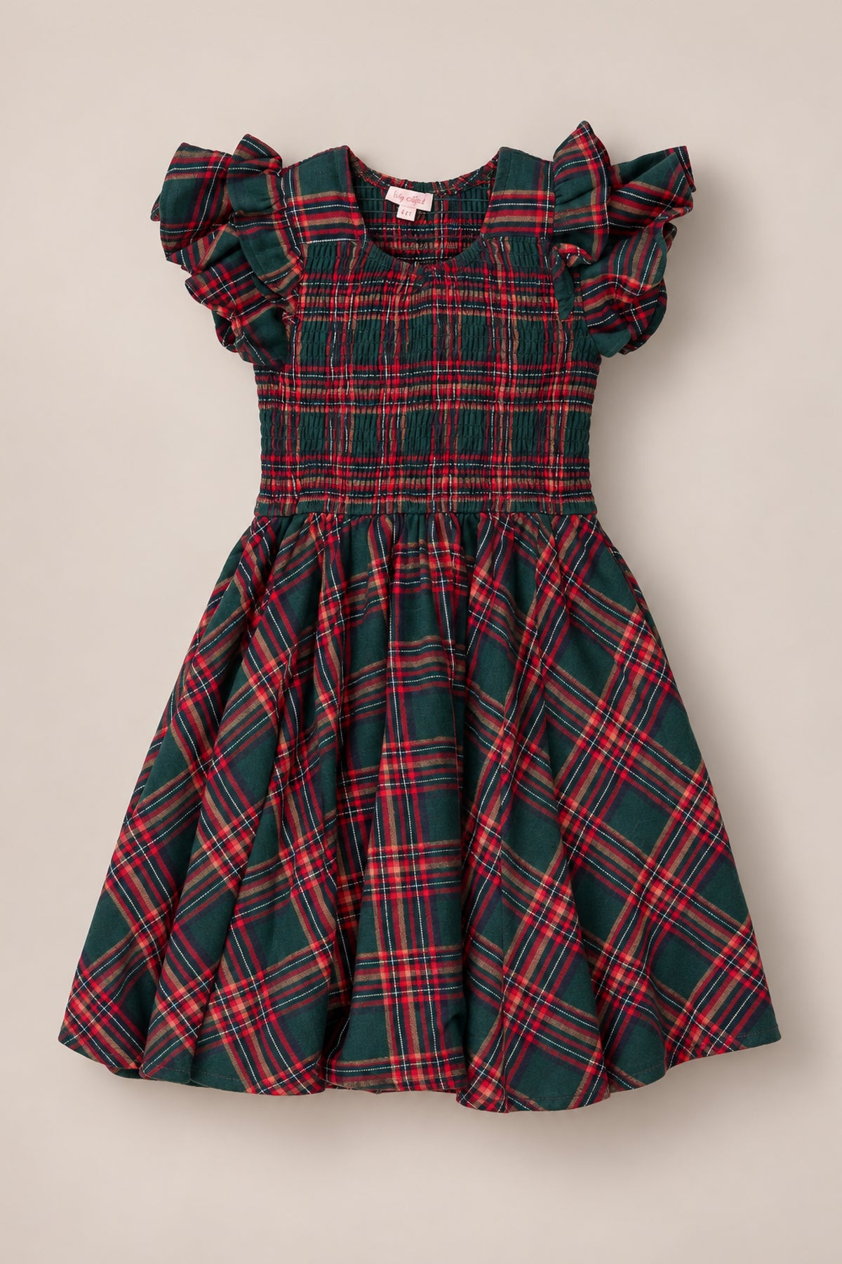 The Mini Hattie Dress in Evergreen Plaid by Ivy City Co, a children’s dress made from soft cotton with short ruffled sleeves, a smocked bodice, and a flared skirt, is displayed on a neutral background.
