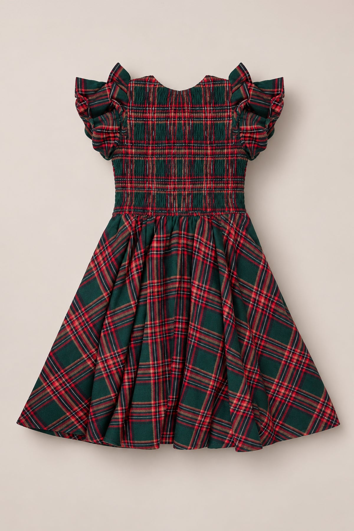 The Mini Hattie Dress in Evergreen Plaid by Ivy City Co features a classic red and green plaid pattern, short ruffled sleeves, a smocked bodice, and a flared skirt. This charming children’s dress is displayed flat on a light background.