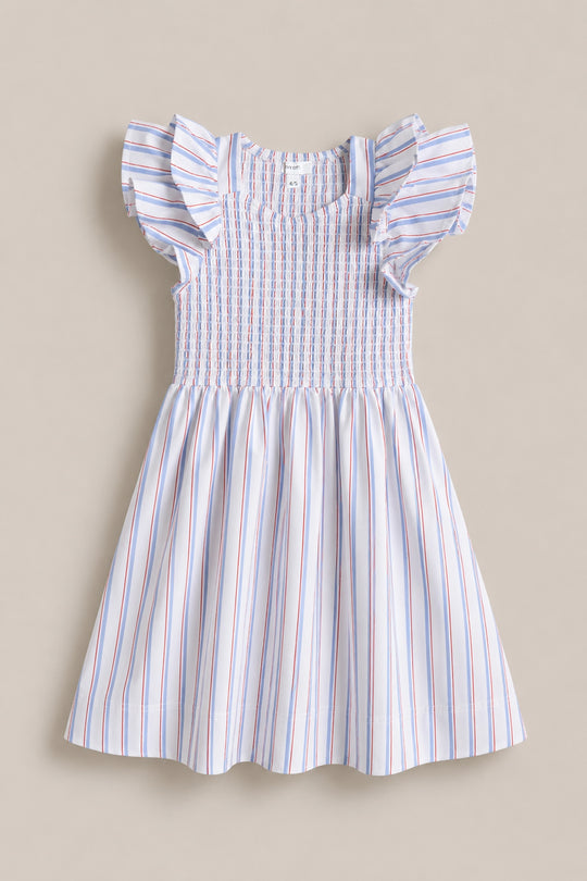 The Mini Hattie Dress in Heritage Stripe by Ivy City Co is a sleeveless dress with ruffled shoulders, smocked bodice, and flared skirt in red, blue, and pink stripes—ideal for July 4th or Mom & Me matching. Shown on a neutral surface.