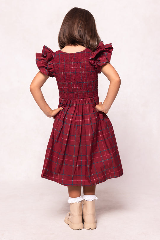 Girl wearing a red plaid dress with ruffled sleeves on a white background