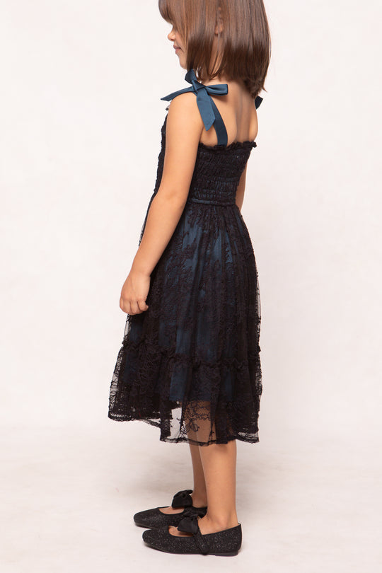 Young girl wearing a black lace dress with a white background