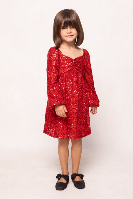 Young girl wearing a red sequin dress on a white background