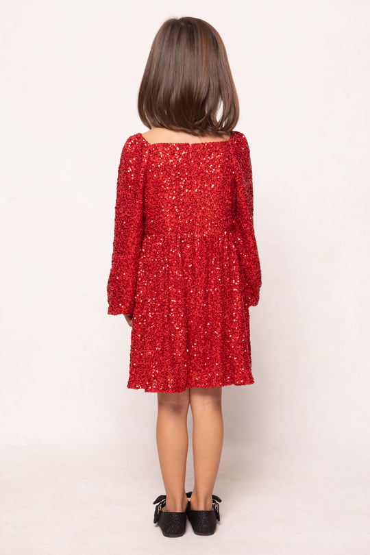 Child wearing a red sequin dress against a white background