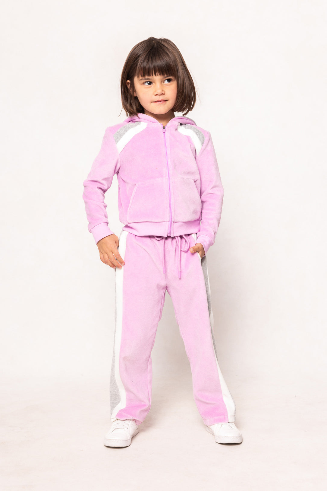 child in a pink sweatsuit against a white background