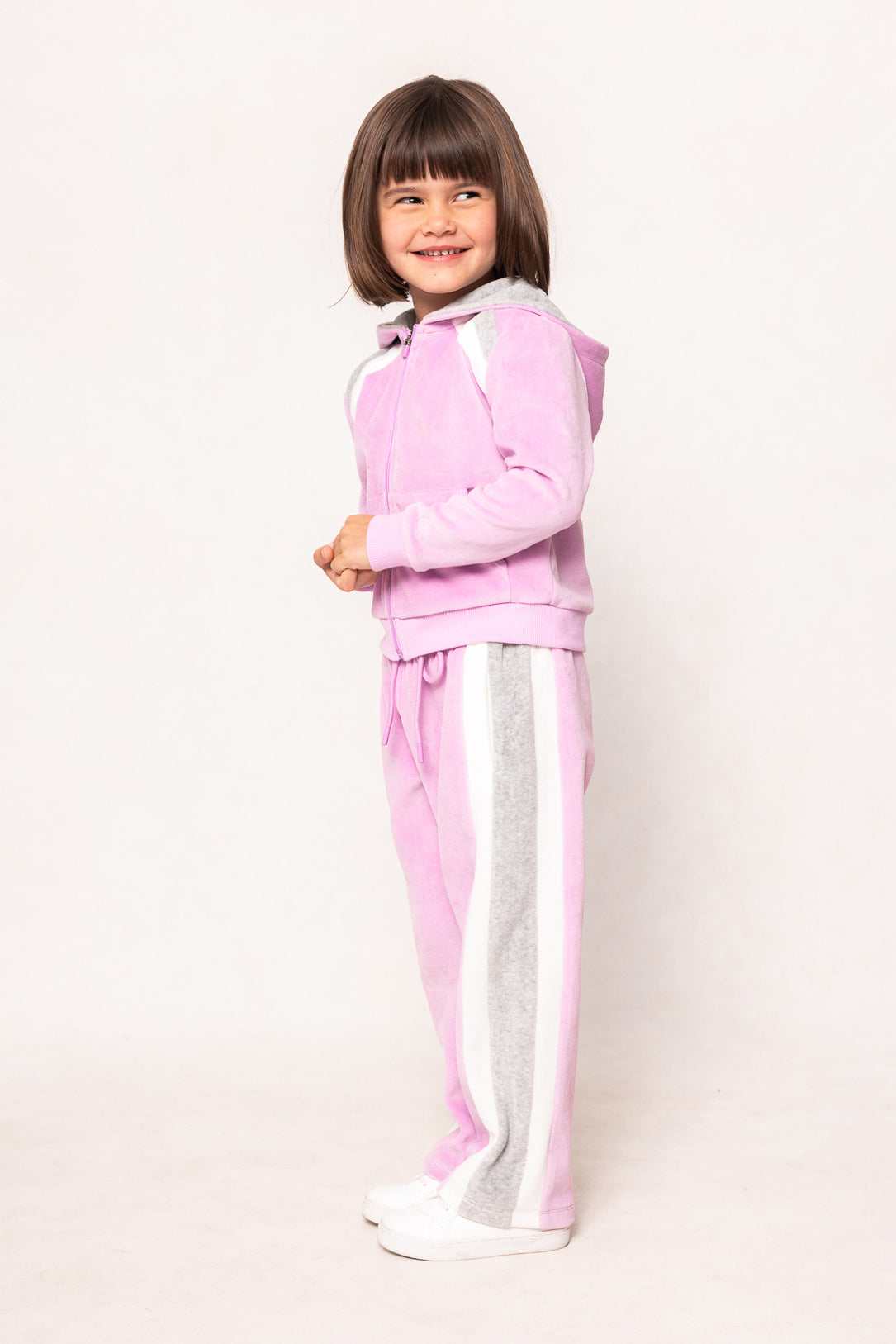 child in a pink sweatsuit against a white background