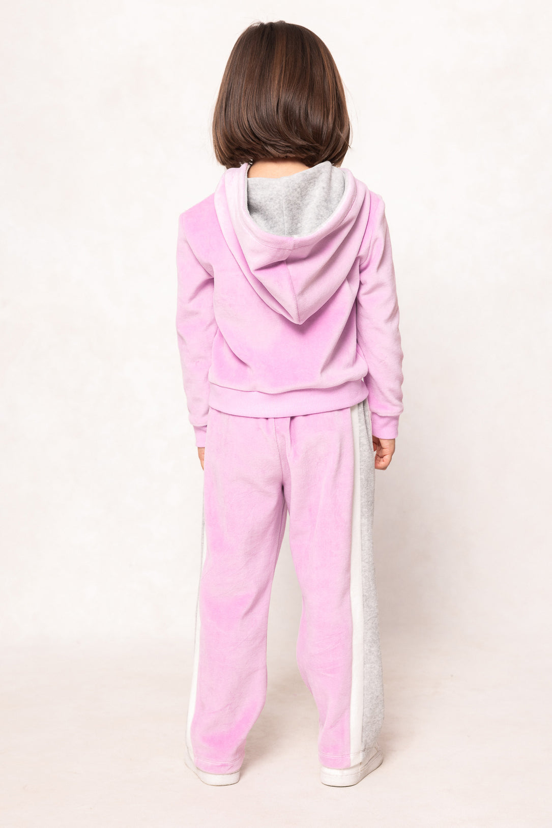 child in a pink sweatsuit against a white background