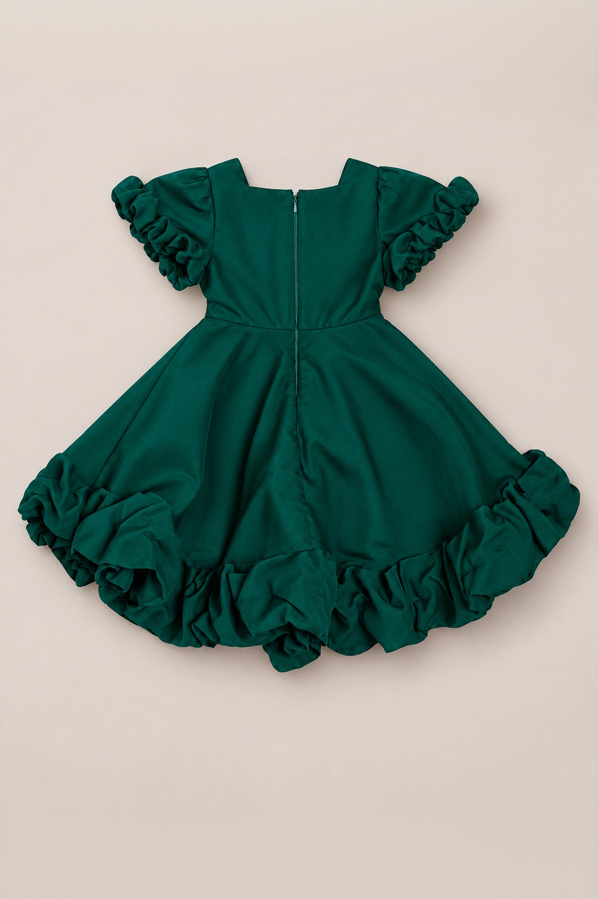 The Mini Kendy Dress in Emerald by Ivy City Co is a green organza dress with short ruffled flutter sleeves and a full skirt with ruffled edges, shown from the back with its visible zipper, laid flat on a neutral background.