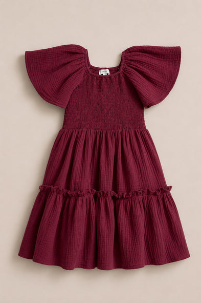 The Ivy City Co Mini Lennon Dress in Wildberry is a berry-pink cotton dress for young children with a smocked bodice, gathered skirt, and flutter sleeves, shown here against a neutral background.
