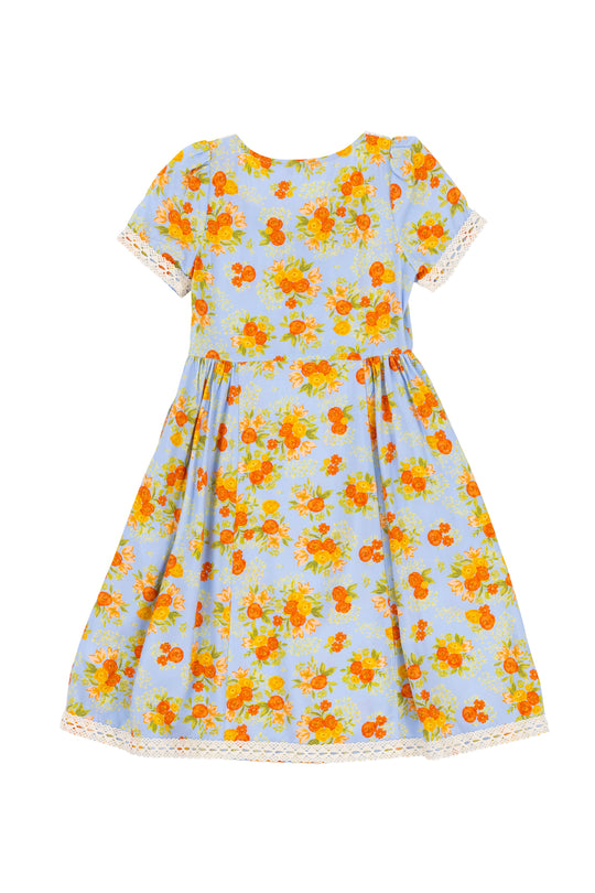 The Ivy City Co Mini Libby Dress in Orange Floral is a short-sleeved, midi dress with an orange floral print on a light blue background and white crochet lace on the sleeves and hem.