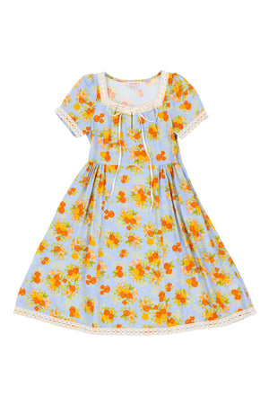 The Mini Libby Dress in Orange Floral by Ivy City Co is a short-sleeved, midi-length dress with an orange floral print on a light blue background, white crochet lace at sleeves, neckline, and hem, plus a decorative chest bow.