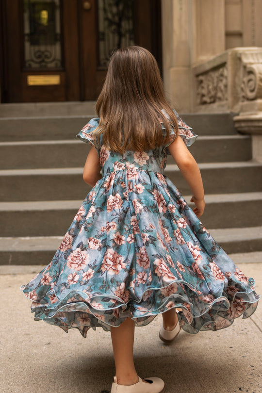 A young girl in the Ivy City Co Mini Lisette Dress in Rose Dusk walks up stone steps toward a building, her back to the camera—the perfect scene for a fall wedding.