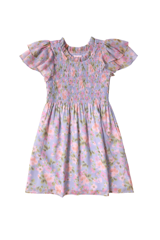 The Ivy City Co Mini Lottie Dress in Vibrant English Garden is shown on a white background, featuring short sleeves, a smocked bodice, ruffled sleeves, and a pastel purple base with pink, green, and yellow floral patterns.