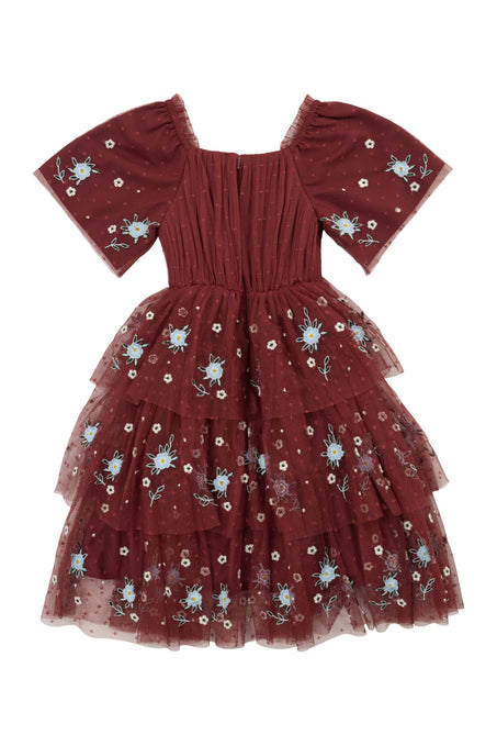The Mini Mabel Dress in Burgundy by Ivy City Co is a girls’ short-sleeved formal dress featuring a square neckline, tulle skirt with tiered layers, and light blue and white floral embroidery.