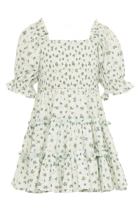 The Mini Madeline Dress in Blue by Ivy City Co features a light blue, knee-length design with a square neckline, smocked bodice, tiered skirt, ruffled details, and a small blue and green floral print for a delicate summer look.