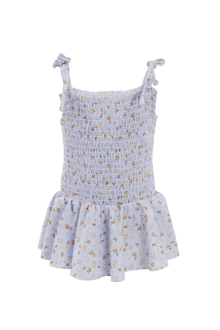The Ivy City Co Mini Maggie One Piece in Blue Ditsy Floral features a shirred bodice, ruffled hem, and adjustable tie straps for a perfect fit.