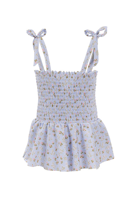 The Mini Maggie One Piece in Blue Ditsy Floral by Ivy City Co features a light blue ditsy floral print, smocked bodice, peplum hem, and adjustable tie straps for a custom fit.