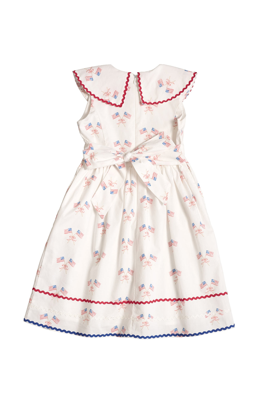 The Ivy City Co Mini Maisy Dress in Star Spangled is a white children’s dress with red and blue trim, a Peter Pan collar, waist bow, and American flag and fireworks print—perfect for the Fourth of July.