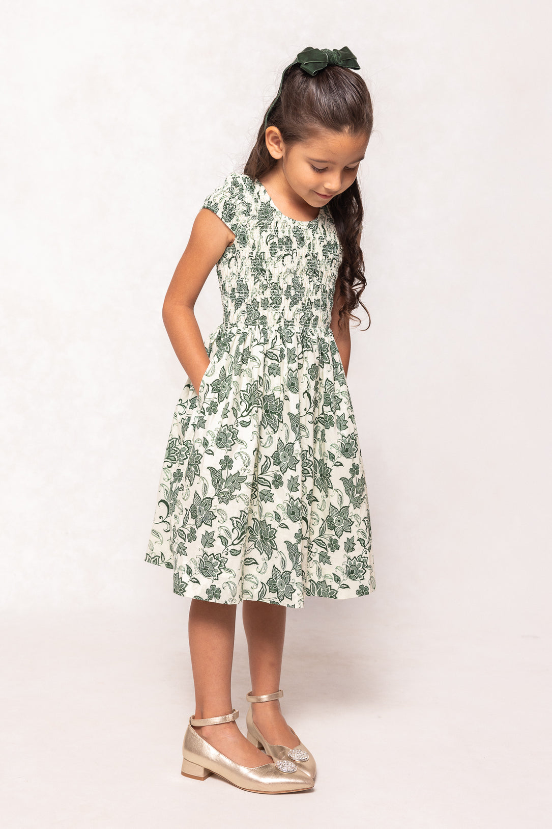 Young girl wearing a green floral dress on a white background