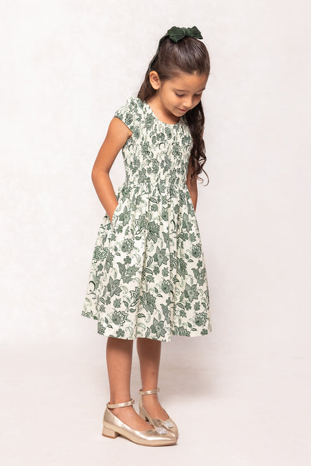 Young girl wearing a green floral dress on a white background