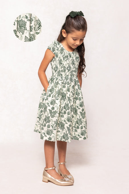 Young girl wearing a green floral dress on a white background