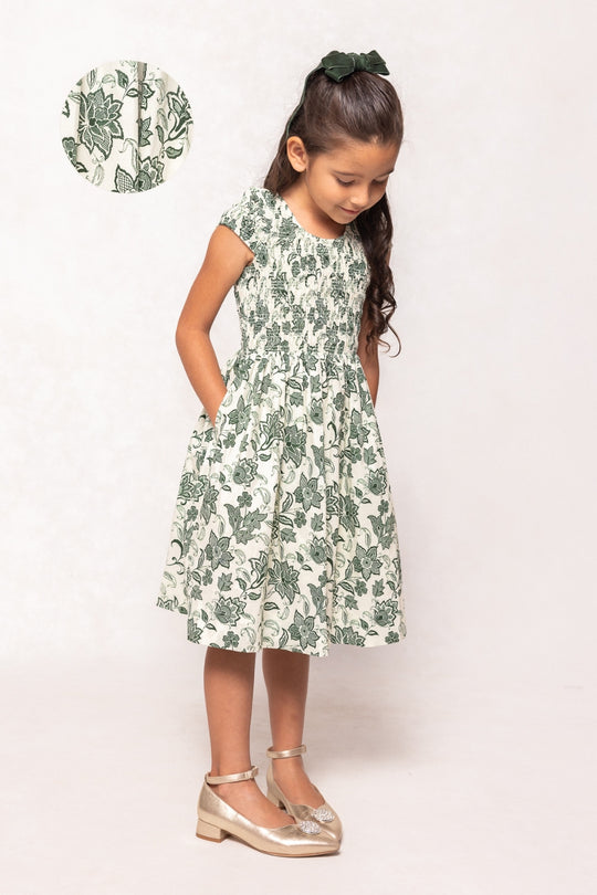 Young girl wearing a green floral dress on a white background