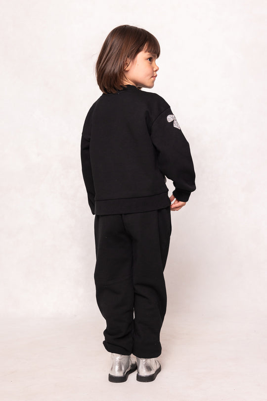 Child in a black sweatsuit against a background