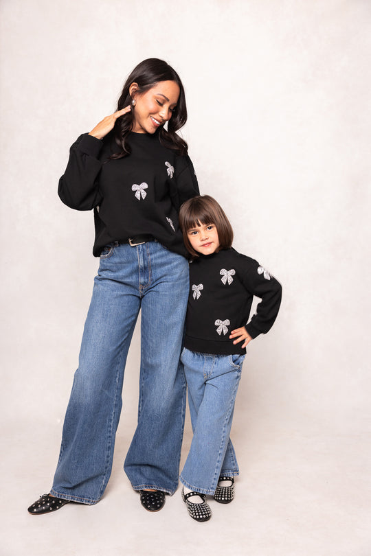woman and child in black sweatshirts against a white background