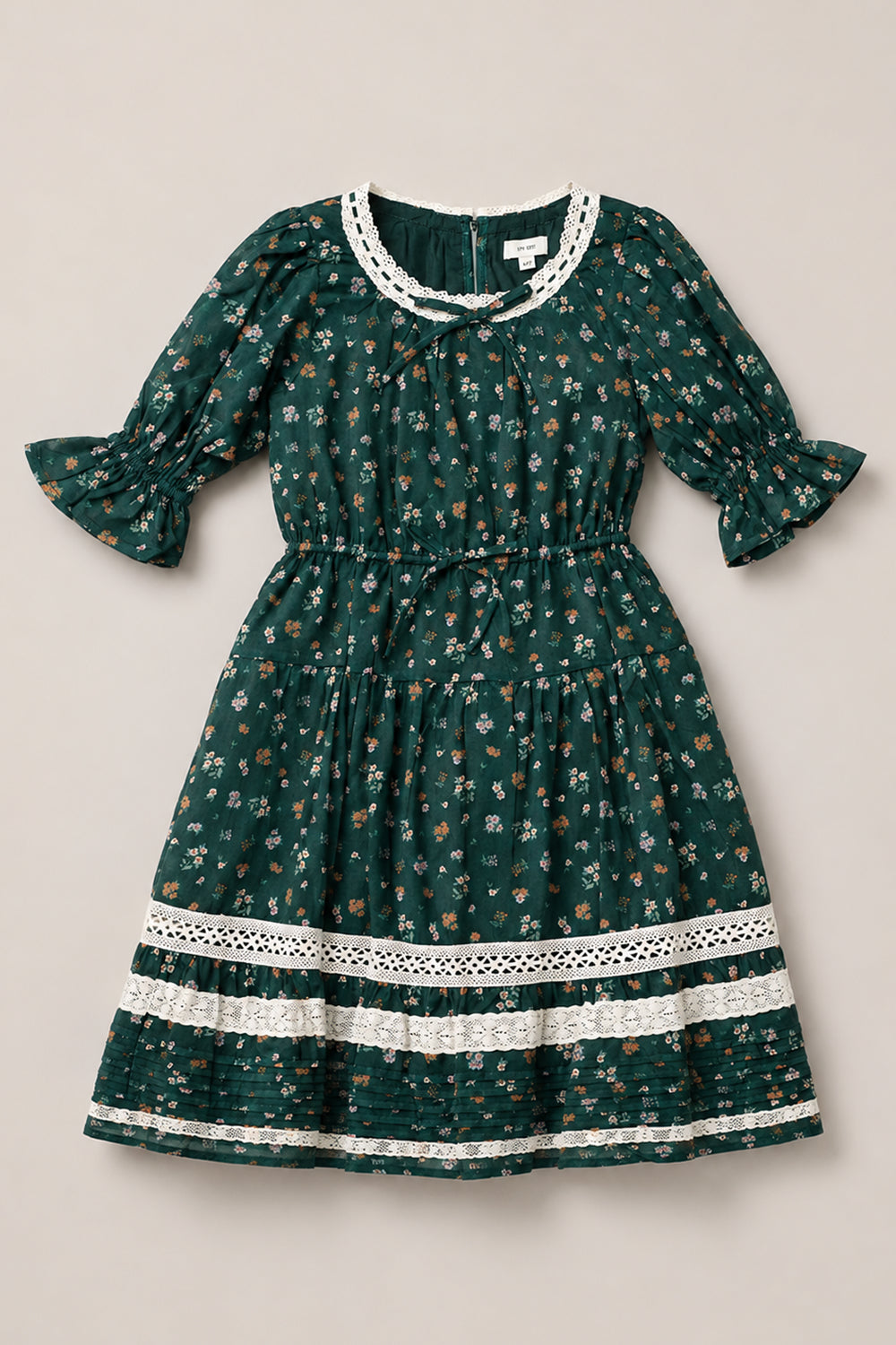 Introducing the Mini Palermo 3/4 Sleeves Dress in Evergreen Lovelorn Ditsy by Ivy City Co—a girls’ cotton dress adorned with a dark green ditsy floral print and delicate white lace accents at the neckline, cuffs, and hem. Featuring elegant 3/4 puff sleeves, a gathered waistline, and a knee-length skirt, this charming piece blends timeless florals with intricate lace details for a captivating look.