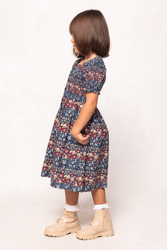 Child wearing a floral dress with beige boots on a white background