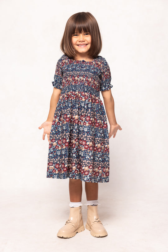 Young girl wearing a patterned dress on a white background