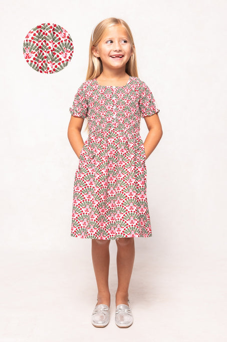 Young girl wearing a floral dress with a matching fabric swatch on a white background