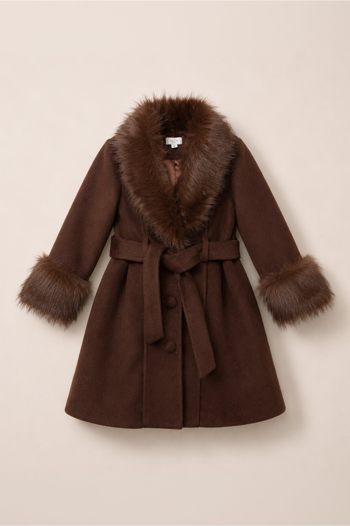 The Mini Pookie Coat in Warm Cocoa by Ivy City Co is a brown wool coat with a wide faux fur collar and cuffs, a matching fabric belt, and large buttons, shown flat on a light beige background—a perfect girls’ fall coat.