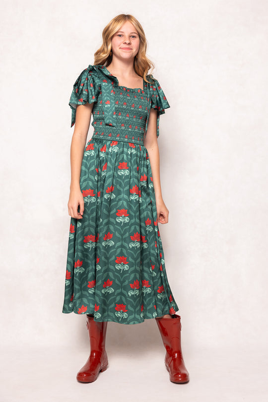 Woman wearing a green dress with red patterns and red boots on a white background
