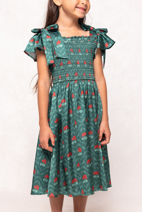 Girl wearing a green dress with red floral pattern on a white background
