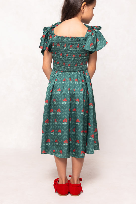 Green dress with red floral pattern worn by a person on a white background