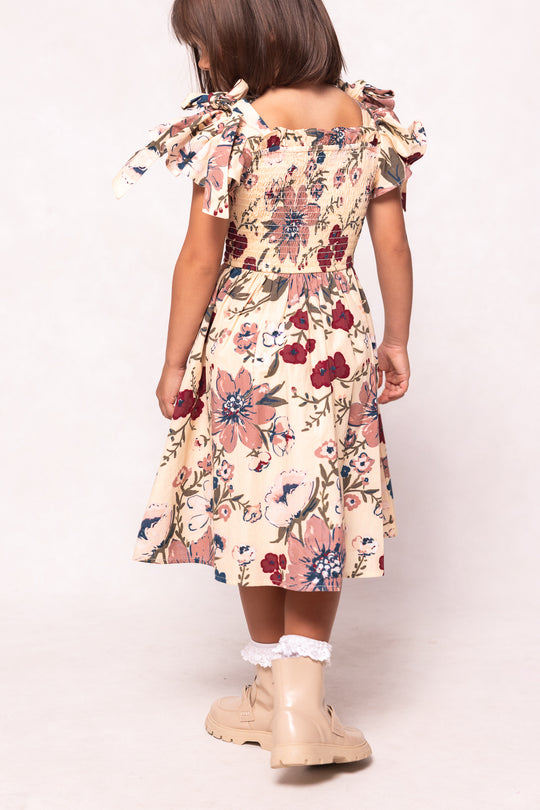 Child wearing a floral dress with ruffled sleeves on a white background