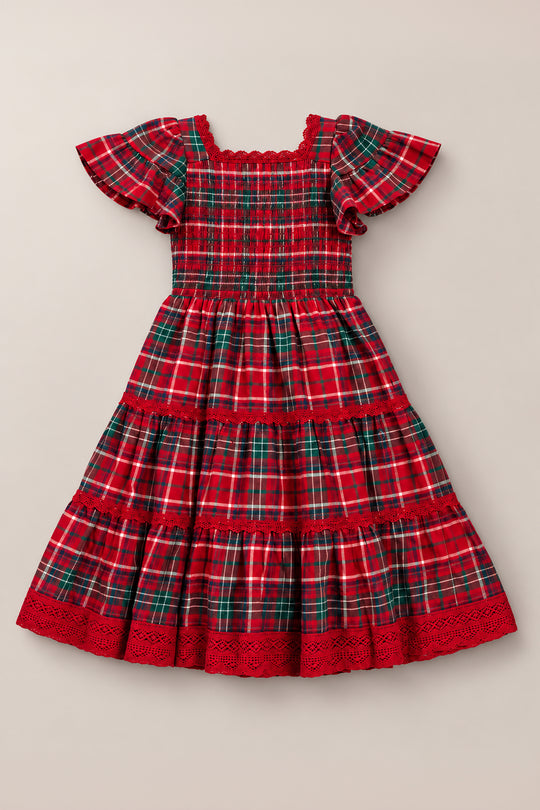 The Mini Rosario Dress in Christmas Cheer Plaid by Ivy City Co is a girls’ holiday dress featuring red and green plaid, short ruffled sleeves, a smocked bodice, tiered skirt, and red lace trim at the hem, displayed flat on a neutral background.