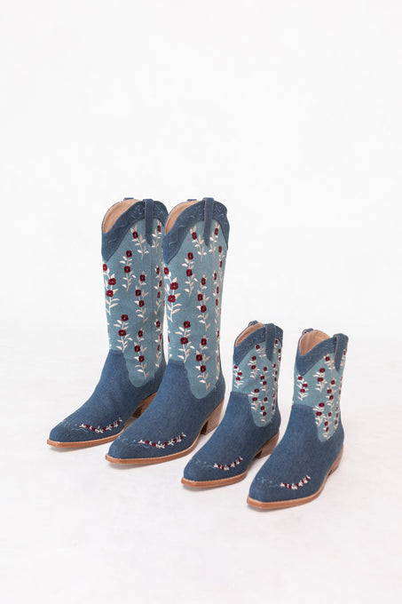 An adult and a child-sized pair of denim cowgirl boots with floral embroidery are displayed side by side, featuring the charming Ivy City Co Mini Rosemary Cowgirl Boots in Denim for little ones.