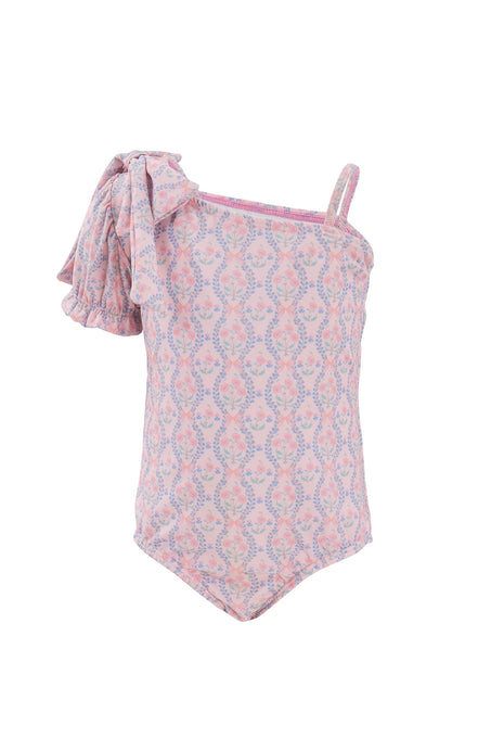 The Ivy City Co Mini Sailor One Piece in Raquel Pink Floral is a stylish girls’ swimsuit featuring a pink floral design, one thin strap, and a large ruffled bow detail for an adorable look.