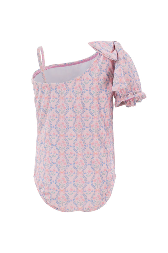 The Mini Sailor One Piece in Raquel Pink Floral by Ivy City Co is a girls swimwear with a sleeveless design, single thin strap, and a large ruffled bow, featuring playful blue and pink floral patterns.