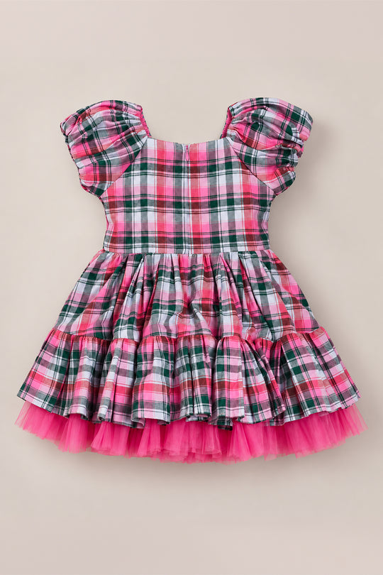 The Mini Scottie Dress in Vibrant Plaid by Ivy City Co is a short-sleeved girls’ dress featuring gathered shoulders, a tiered ruffle skirt, and bright pink tulle trim at the hem, shown on a beige background—an adorable choice for festive Christmas celebrations or holiday parties.
