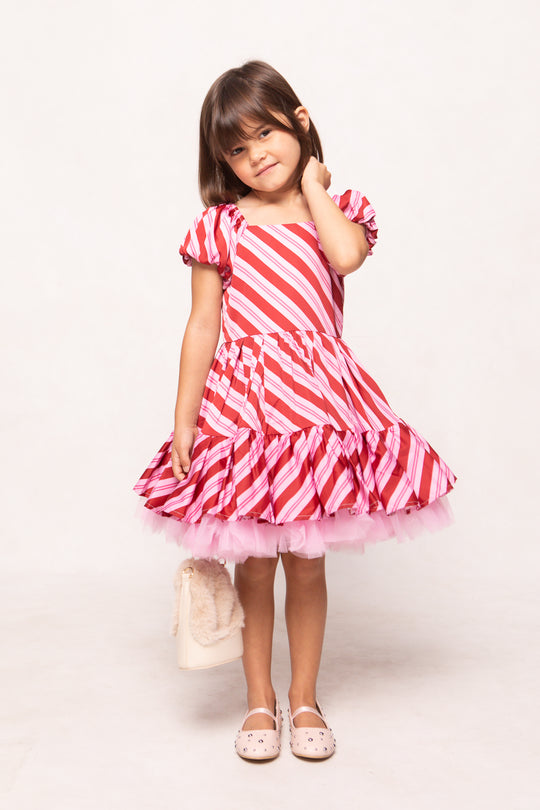 Young girl wearing a red and white striped dress on a white background