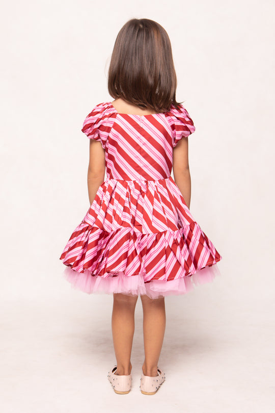 Young girl wearing a red and pink striped dress on a white background