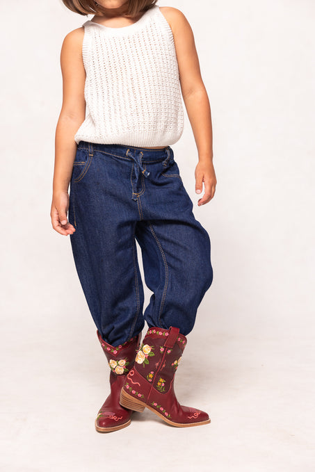 Child wearing blue jeans and red floral boots on a white background