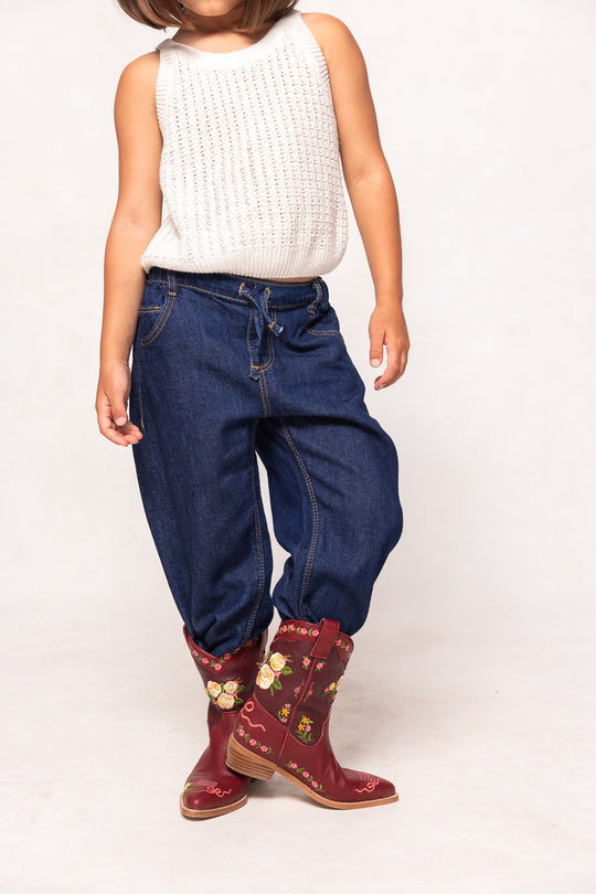 Child wearing blue jeans and red floral boots on a white background