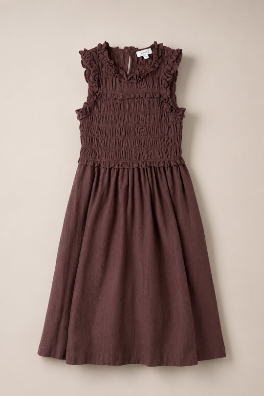Sleeveless, knee-length Teen Simone Dress in a warm cocoa color from Ivy City Co, featuring ruffle details on the shoulders and neckline, a gathered smocked bodice, and convenient pockets.