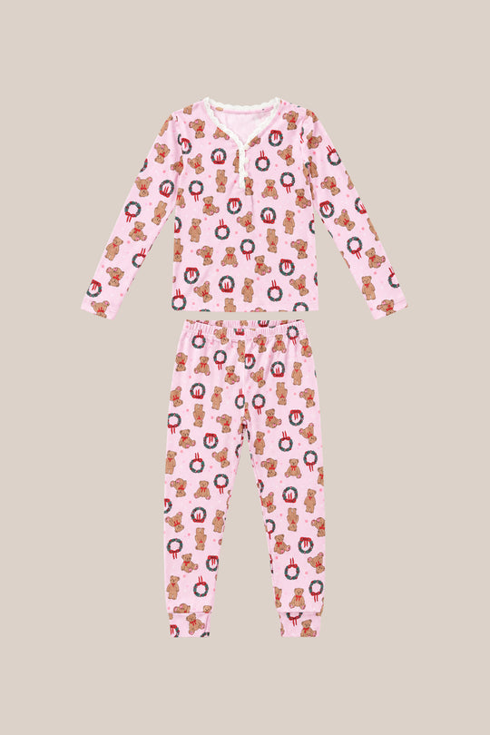 The Mini So Soft Henley Pajama Set in Teddy Bear Wreaths by Ivy City Co is a two-piece pink pajama set with long sleeves and pants, featuring teddy bear wreath prints, laid flat on a beige background.