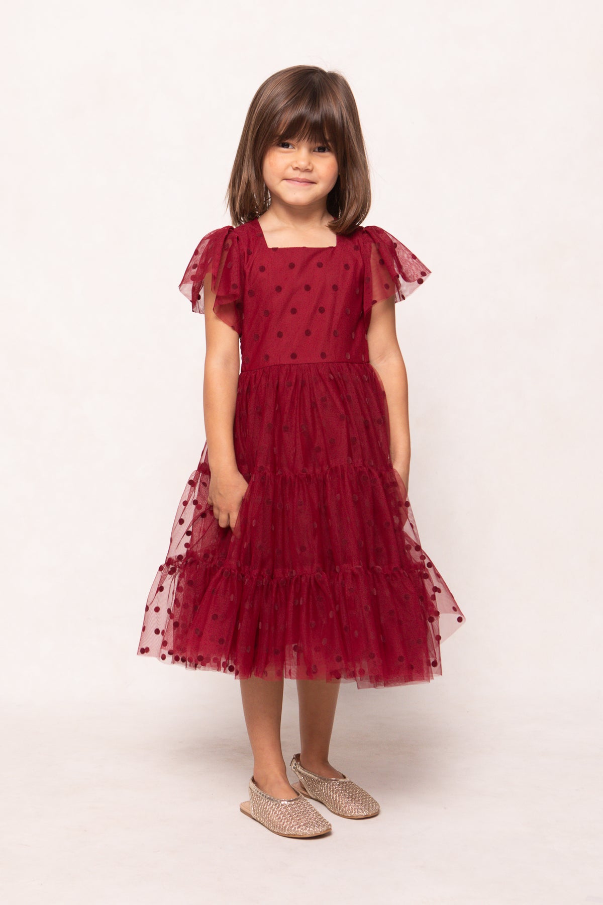 Young girl wearing a red dress with a white background