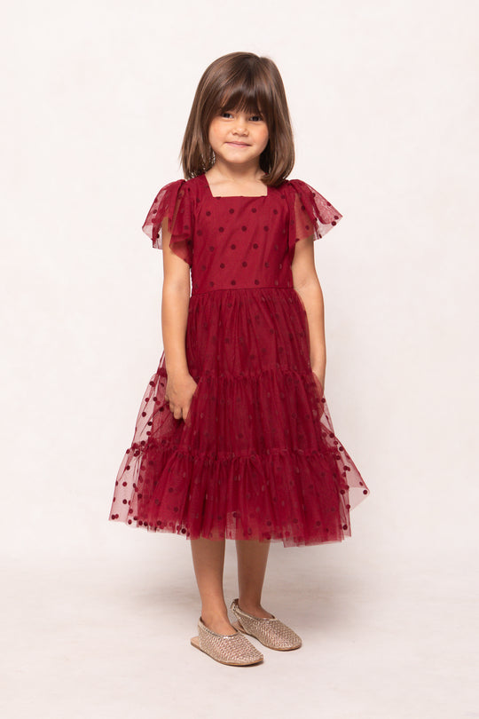 Young girl wearing a red dress with a white background