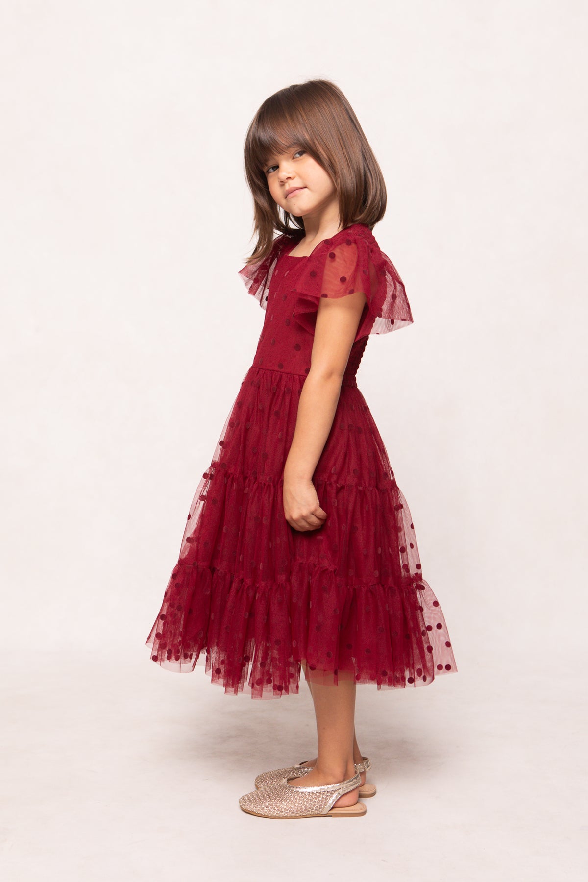 Young girl wearing a red dress with ruffled sleeves on a white background